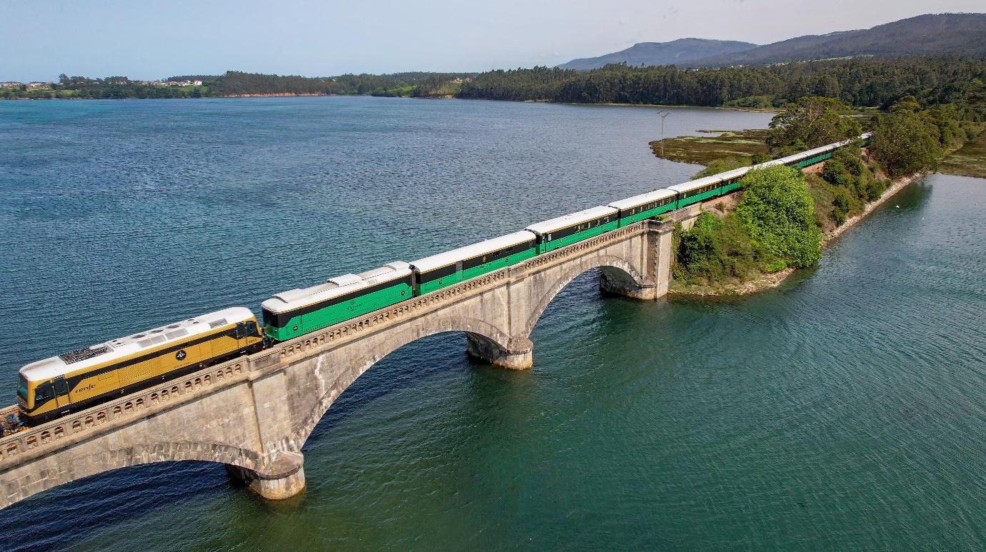 Costa Verde Express auf einer Brücke über die grüne Küste Nordspaniens